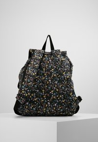 Sac à dos fleuri avec un fond noir, orné de petites fleurs colorées. Confectionné en tissu, il possède des bretelles réglables et une poignée supérieure.