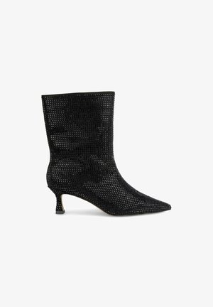 Bottines noires avec un bout pointu, fabriquées en matériau en maille texturée, dotées d'un petit talon et d'un design minimaliste.