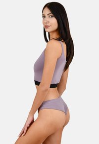 Paarse cropped tanktop met zwarte band, gecombineerd met bijpassende paarse bikini bottoms. Gladde textuur, aansluitend ontwerp.