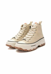 Zapatillas altas beige con una suela blanca gruesa, una franja negra y una suela texturizada en color marrón claro. Presentan un diseño con cordones y etiquetas en la lengüeta.