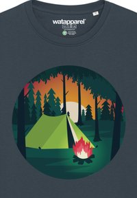 Donkerblauwe T-shirt met een circulaire afbeelding van een groene tent, een kampvuur en bomen, tegen een zonsondergang achtergrond in oranje en groene tinten.