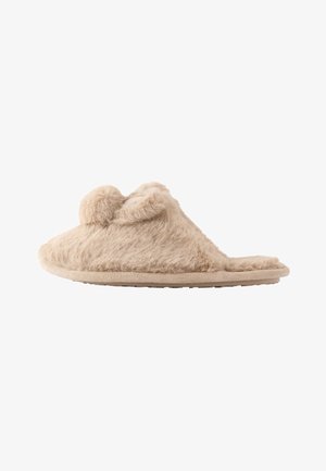 Beige flauschiger Hausschuh zum Hineinschlüpfen mit zwei Pompons oben und einer flachen Sohle, für den Innenbereich konzipiert.