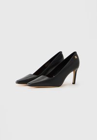 Pair of black leather pointed-toe high heels with slim stiletto heels and gold logo detail on the side.
