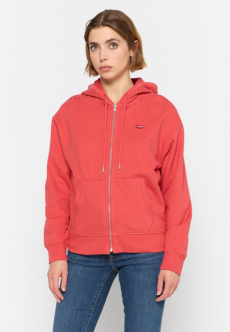 Cappuccio rosso con zip, con cappuccio foderato, due tasche frontali e un piccolo logo Levi's sul petto. Realizzato in tessuto morbido e testurizzato.