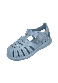 Sandalia de goma azul claro con diseño abierto, correa ajustable y patrón trenzado en la parte frontal. Presenta orificios de ventilación en los laterales.