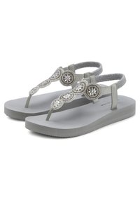 Grijze flip-flops met een gestructureerde zool, voorzien van een decoratieve band versierd met ronde, glinsterende accenten en een gladde afwerking.