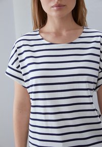 Navy and white striped T-shirt with a round neckline and short sleeves, made from soft cotton fabric, featuring a loose fit and casual design.