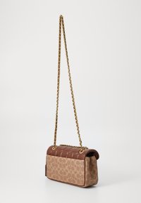 Borsa a spalla in pelle marrone con parte superiore trapuntata, tracolla in catena dorata e una stampa marrone a motivo sul davanti. Forma rettangolare con patta.