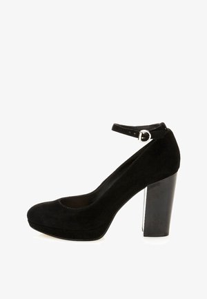 Chaussure à talon haut en suede noir avec un bout arrondi et une bride ajustable à la cheville. Dotée d'un talon épais et d'une texture lisse.