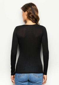 Sort langærmet top i let materiale med en tætsiddende pasform. Har en rund halsudskæring og en glat tekstur.
