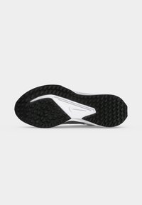 Sort og hvid atletisk sål med tekstureret greb og et synligt swoosh-logo i midten mod en ensartet lys baggrund.