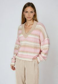 Knitted sweater with a V-neck, featuring horizontal stripes in pink, cream, and beige. Loose fit with ribbed cuffs and hem.
