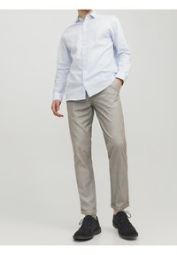 Camicetta azzurro chiaro, pantaloni grigi slim-fit e scarpe nere. La camicia ha una consistenza morbida; i pantaloni presentano un motivo sottile e un design sartoriale.