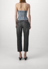 Top in denim a corsetto con dettagli arricciati e design senza spalline, abbinato a jeans scuri e larghi con tasche posteriori e orli sfrangiati.