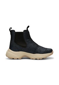 Botín de tobillo negro y azul marino sin cordones, con parte superior brillante, paneles laterales elásticos y suela gruesa beige con agarre texturizado.