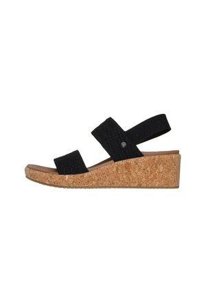 Sandalias de cuña negras con dos correas elásticas, plantilla de corcho y suela de goma, que presentan un diseño texturizado en la parte superior y un acento de logo metálico.