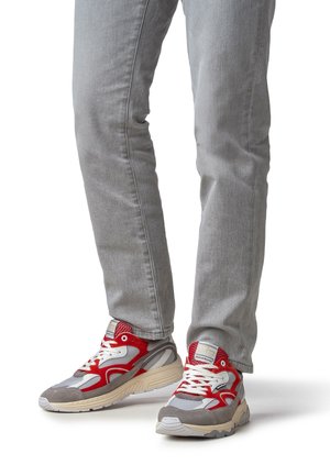 Baskets de sport rouges et grises en mesh et suède, avec des lacets blancs, des semelles texturées et une languette rembourrée.