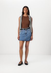 Bruine tanktop, gestreepte mouwloze cardigan, denim minirok, zwarte riem met ronde gesp, zwarte loafers, gladde texturen, casual pasvorm.
