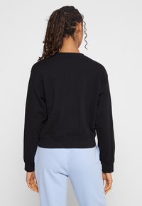 Czarny skrócony sweatshirt z prążkowanymi mankietami i dołem, o gładkiej fakturze. Tył prezentuje klasyczny fason z okrągłym dekoltem.