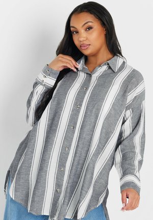 Camicia a righe grigie e bianche con bottoni realizzata in tessuto leggero; presenta un colletto, una pattina con mezzo bottone e maniche lunghe con polsini.
