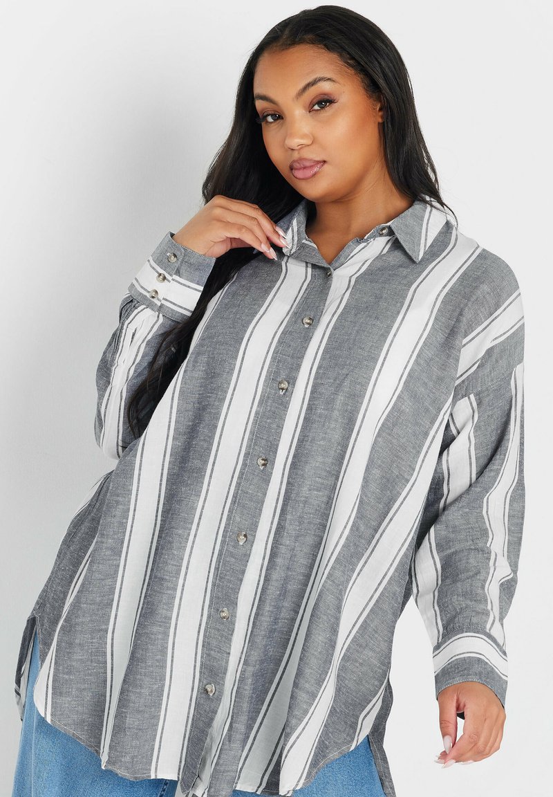 Camisa de botones a rayas gris y blanca hecha de tela ligera; cuenta con un cuello, tapeta de medio botón y mangas largas con puños.
