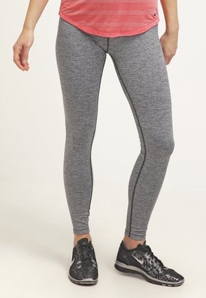 Leggings de sport gris avec une texture chinée, offrant une coupe près du corps et des coutures latérales contrastées. Associés à des chaussures de sport noires.