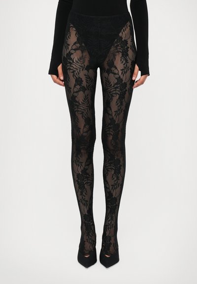 Schwarze, transparente Strumpfhosen mit floralem Spitzenmuster; hoher Bund; glatte Textur; kombiniert mit schwarzen High Heels.