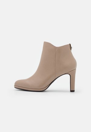 Bottine en cuir beige avec un talon haut et fin et un bout arrondi, présentée de profil sur un fond blanc uni.