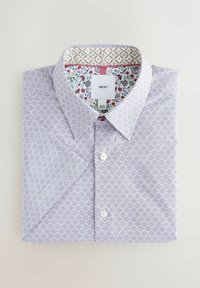 Chemise blanche et violette à motifs avec un col pointu, présentant une impression florale et géométrique à l'intérieur du col et une étiquette portant la marque "NEXT".