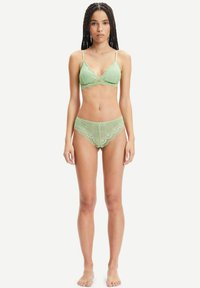 Helles grünes Spitzenunterwäscheset mit einem Soft-Cup-BH mit gewellten Rändern und passenden Boyshorts mit geometrischen Mustern.