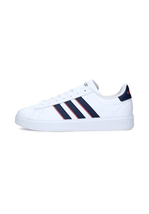 Zapatilla deportiva blanca con tres rayas marinas y acentos rojos; parte superior de cuero suave, suela plana, punta redonda y diseño con cordones.