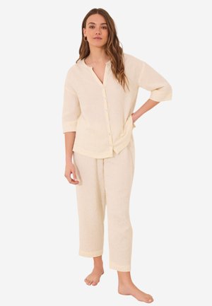 Light yellow pajama set made of textured fabric, featuring a button-up shirt with three-quarter sleeves and cropped pants with a cuffed hem.