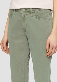 Hellgrüne Baumwolljeans mit tailliertem Design, ausgestattet mit Vorderstaschen und standardmäßiger Nähte. Der Bund verfügt über einen Metallknopfverschluss.