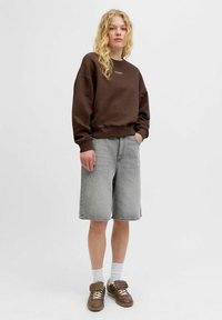 Bruine sweatshirt met ronde hals, grijze spijkerbroek shorts, witte enkelsokken en bruine sneakers. Casual outfit met een losse pasvorm en zachte texturen.