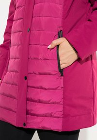 Fuchsia padded jacket with smooth fabric, featuring horizontal quilted texture, a zipper pocket, and black snap buttons.
