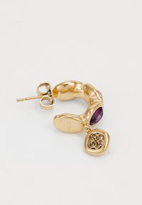 Gold hoop earring with a polished finish, featuring a deep purple gemstone and a decorative charm with a cut-out design.