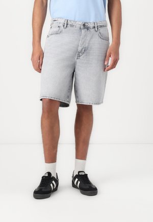 Light grey denim shorts with a straight fit, five-pocket design, and stitched hem, paired with black sneakers and white socks.