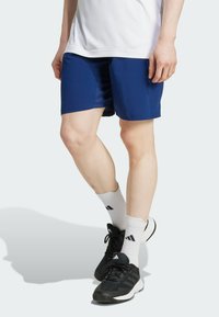 Marina atletiska shorts med en slät yta, med en enfärgad design och en medellång klippning. Bärs med vita strumpor och svarta atletiska skor.