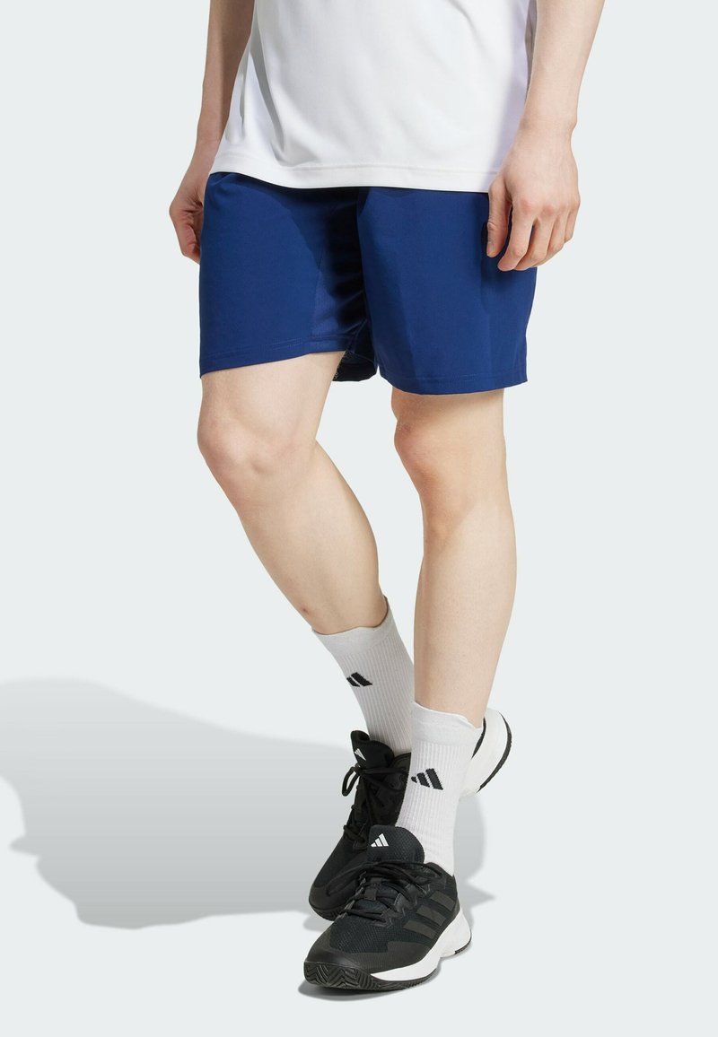 Marina atletiska shorts med en slät yta, med en enfärgad design och en medellång klippning. Bärs med vita strumpor och svarta atletiska skor.