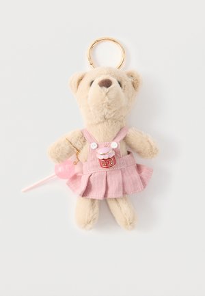 Porte-clés ours en peluche beige portant une robe rose avec un patch "You're my jam", tenant un petit accessoire sucette rose.