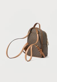 Brązowy plecak z nadrukiem, z jasnobrązowymi skórzanymi paskami i akcentami. Posiada złoty zamek błyskawiczny i wyraźny wzór na całej powierzchni.