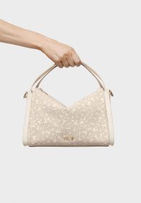 Kremowa torebka o teksturowanym wzorze, złotych detalach i V-kształtnym projekcie. Posiada krótkie uchwyty i detal z logo z przodu.