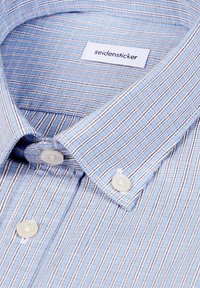 Chemise à rayures bleu clair avec boutons blancs et une étiquette de marque Seidensticker visible à l'intérieur du col.