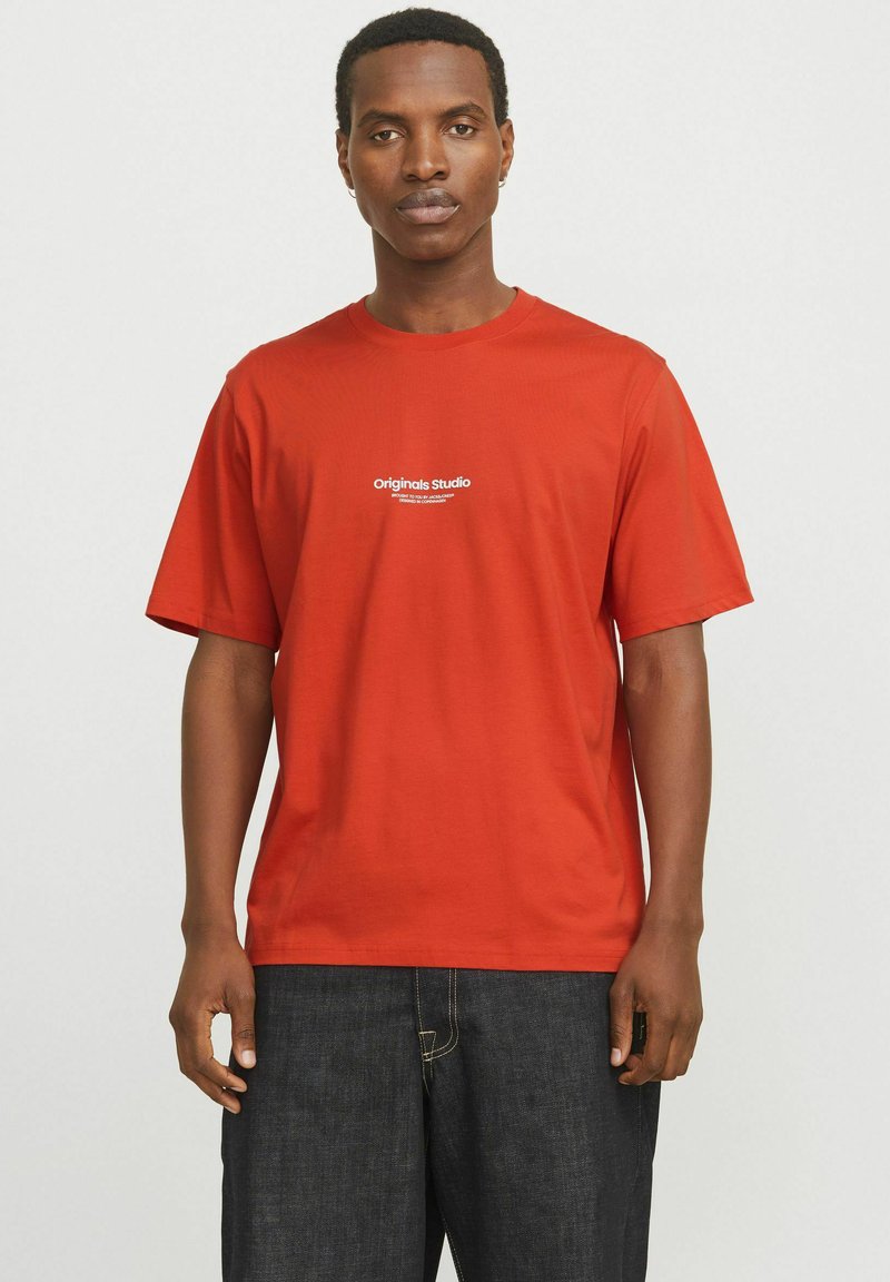 Rotes Baumwoll-T-Shirt mit kurzen Ärmeln, auf der Vorderseite mit dem weißen Text "Originals Studio" bedruckt. Glatte Textur und lockere Passform.