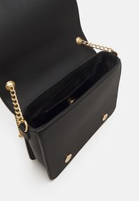 Borsa a tracolla in pelle nera con catena dorata, chiusura a pressione magnetica e finitura liscia. L'interno presenta una tasca e una fodera morbida.