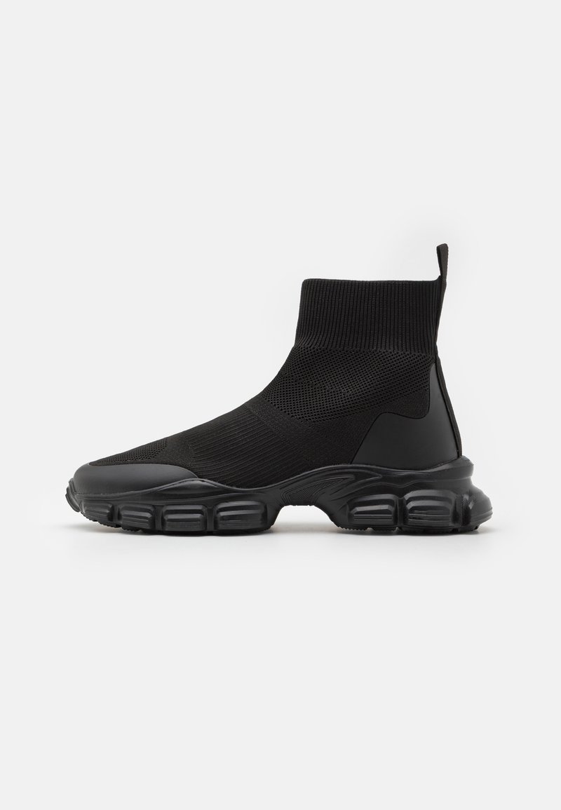 Baskets montantes noires style chaussette avec tige en maille texturée, semelle épaisse segmentée et languette au talon, vues de côté.