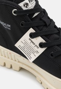 Czarny tenisówka na płótnie o teksturowanej powierzchni, z kremową gumową podeszwą i oznaczoną metką z napisem "Authentic Style". Posiada czarne sznurowadła i oczka.