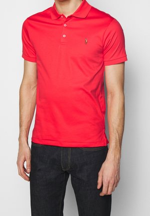 Polo rouge en tissu léger, avec un col classique, une patte de boutonnage à trois boutons et un logo brodé sur la poitrine.