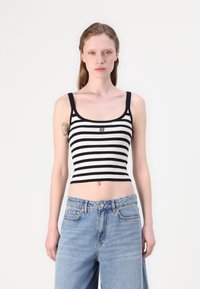Černobílý pruhovaný žebrovaný crop top s širokými ramínky a přiléhavým střihem, doplněný o světle modré džíny s vysokým pasem.