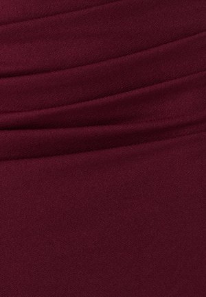 Priblizni prikaz nabora tkanine tamnocrvene boje s glatkom, blago teksturiranom površinom i nježnim preklopima.